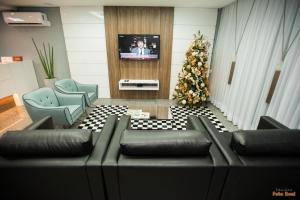 a living room with a couch and a christmas tree at SH Hotel Capinzal Premium in Capinzal
