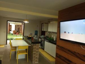 cocina con TV de pantalla plana y mesa con sillas en Apt no Taiba Beach Resort en Taíba