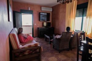 two people sitting in chairs in a living room at Apartamentos Los Panchos in Ruidera