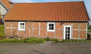 a brick building with an orange roof and two windows at Gemütliche Ferienwohnung, Ländlich und Stadtnah, ruhig gelegen in Rheda-Wiedenbrück