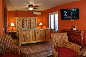 a living room with orange walls and two chairs at La Posada Hotel and Gardens in Winslow