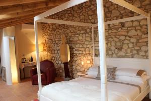 a bedroom with a bed and a stone wall at Corte Tre Vigne in Marano di Valpolicella