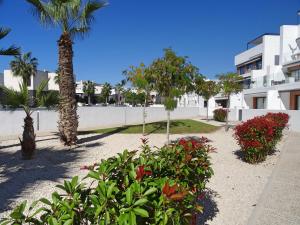 a garden with palm trees and flowers in front of a building at Apartment Orihuela Costa Golf 662 in Los Dolses