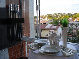 a table with plates and a glass vase on a window at Apartamento Cristal in Porto Alegre