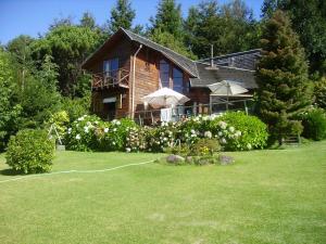ein Haus mit einem Rasen davor in der Unterkunft Casa Orilla Lago Villarrica in Villarrica