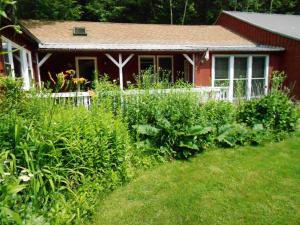 a garden in front of a red house at Cavalier Cottage B&B in Shelburne Falls