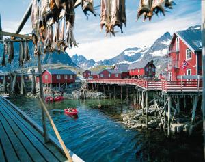 uma ponte sobre um rio com casas vermelhas e montanhas em Å Rorbuer - by Classic Norway Hotels em Å