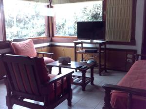 sala de estar con sofá y TV en Cabañas El Pedregal en Sierra de los Padres