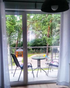 a window view of a patio with a table and chairs at Apartament Ku Morzu II Ustronie Morskie in Ustronie Morskie