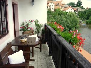 捷克克魯姆洛夫的住宿－普拉斯維卡119賓館，一个带长椅和鲜花的阳台,以及河流