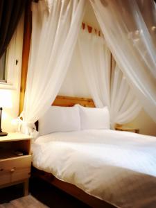 une chambre avec un lit à baldaquin avec des rideaux blancs dans l'établissement Seed House, à Taïtung