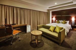 JR-EAST Hotel Mets Niigata في نيغاتا: غرفة في الفندق بها سرير وأريكة ومكتب