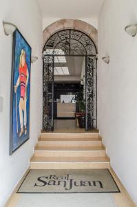 a hallway with a staircase with a gate and a painting at Hotel Real San Juan in Morelia