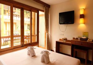 ein Hotelzimmer mit 2 Handtüchern auf einem Bett und einem TV in der Unterkunft Vieng Mantra Hotel in Chiang Mai