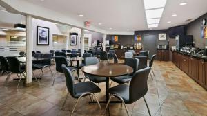 a waiting room with tables and chairs in a restaurant at Best Western Airport Inn in Calgary