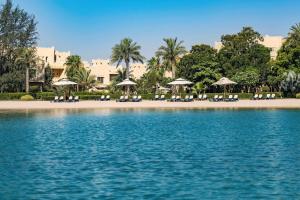 a beach with chairs and umbrellas on the beach at Grand Hyatt Doha Hotel & Villas in Doha