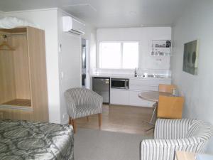 a small kitchen with a bed and a table and chairs at Anchorage Motel Apartments in Te Anau