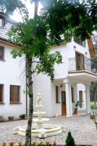 a white building with a statue in front of it at Dworek Nadmorski in Bobolin