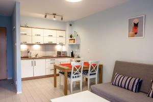 kuchnia oraz salon ze stołem i kanapą w obiekcie Apartament Kapitański Bursztynowe Komnaty w Darłówku