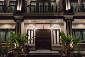 a house with a black door and two plants at The Besavana Phuket - SHA Extra Plus in Phuket Town