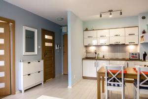 kuchnia z białymi szafkami, stołem i krzesłami w obiekcie Apartament Kapitański Bursztynowe Komnaty w Darłówku