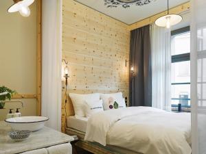 
a bedroom with a white bed and white walls at 25hours Hotel The Royal Bavarian in Munich
