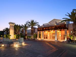 a large building with palm trees in front of it at Aldemar Knossos Villas in Hersonissos