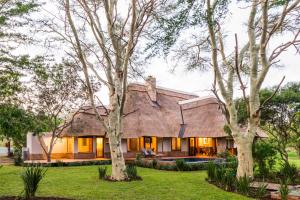 a house with a thatched roof and trees at Hluhluwe Lodge by ANEW in Hluhluwe