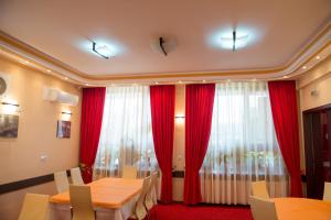 una sala da pranzo con tende rosse e tavolo e sedie di Pensiunea President a Deva