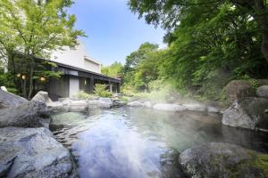 una piscina de agua con rocas frente a un edificio en Kasuga no Mori, en Saku