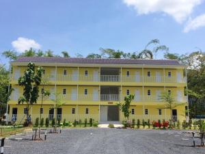 ein großes gelbes Apartmenthaus mit Parkplatz in der Unterkunft River&Mountain Resort in Nakhon Nayok