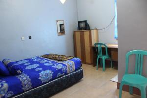a bedroom with a bed and a desk and chairs at Penginapan Artha in Praya