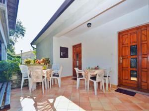 Un patio con sillas y mesas blancas y una puerta de madera. en Apartment Bruna 653, en Rabac
