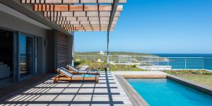 a patio with chairs and a swimming pool on a house at Romans Villa in Gansbaai