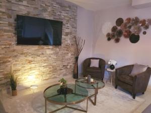 a living room with two chairs and a television on a brick wall at 135m2 - Villa, 5 min to the park - DISNEY MAGICAL HOMES, PARIS in Magny-le-Hongre