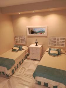a bedroom with two beds and a dresser and a window at Marbella House in Marbella