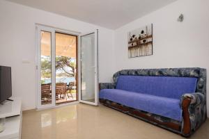 sala de estar con sofá azul y puerta corredera de cristal en Pavao Apartments, en Vrboska