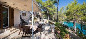 a table and chairs on a deck with a view of a river at Pavao Apartments in Vrboska