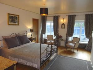 a bedroom with a bed and chairs and windows at Manoir De Savigny in Valognes