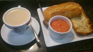 un piatto con una tazza di caffè e pane e una tazza di zuppa di V Hotel ad Arroyomolinos