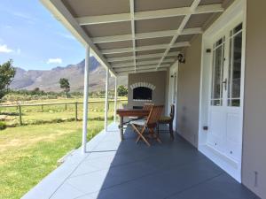 a patio with a table and a fireplace on a house at Olive Cottage in Franschhoek