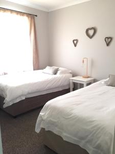 Un dormitorio con 2 camas y una ventana con corazones en la pared. en Olive Cottage en Franschhoek