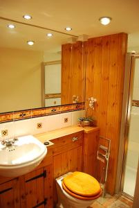 a wooden bathroom with a toilet and a sink at Swallows' Barn in Corby