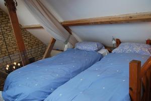 two beds in a attic room with blue sheets at Swallows' Barn in Corby
