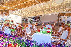 un restaurant avec des tables et des chaises blanches et des fleurs violettes dans l'établissement Hotel Dream Of Side, à Sidé