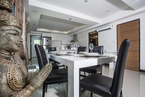 a dining room with a table with chairs and a statue at ViLLa JUNGLE 3 BEDROOMS in Kamala Beach
