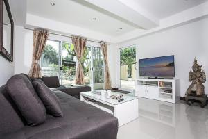 a living room with a couch and a flat screen tv at ViLLa JUNGLE 3 BEDROOMS in Kamala Beach