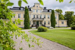 a large white house with trees in front of it at Färna Herrgård & Spa in Färna
