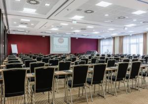 a conference room with tables and chairs and a screen at Best Western Premier Novina Hotel Regensburg in Regensburg