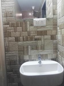 a white sink in a bathroom with a tile wall at golden dormitory in Mumbai